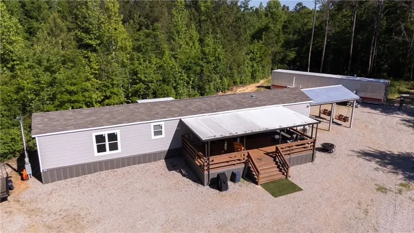A welcoming front porch extends from this single-story residence, set against a backdrop of mature trees.