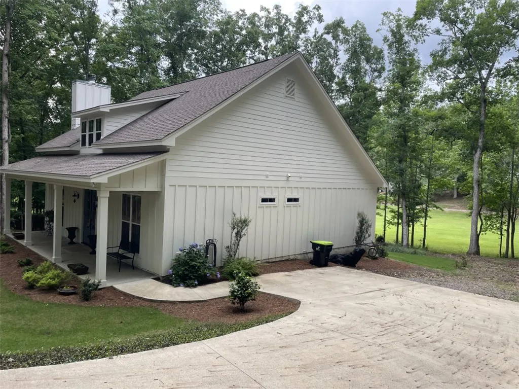 A charming farmhouse-style home with a welcoming front porch set against a backdrop of lush trees.