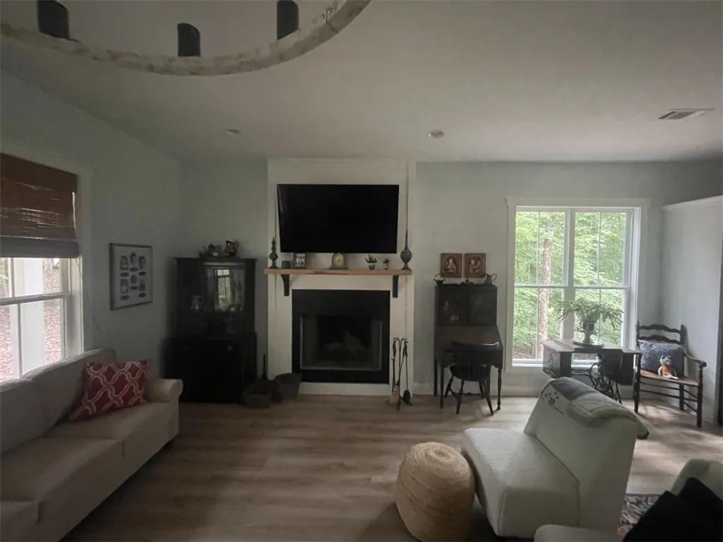 An inviting living room, where light wood flooring complements the bright walls and a prominent fireplace.