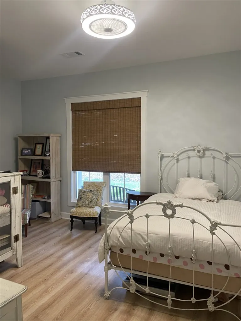 Comfortable bedroom features light wood flooring and a stylish ceiling fan with integrated lighting.