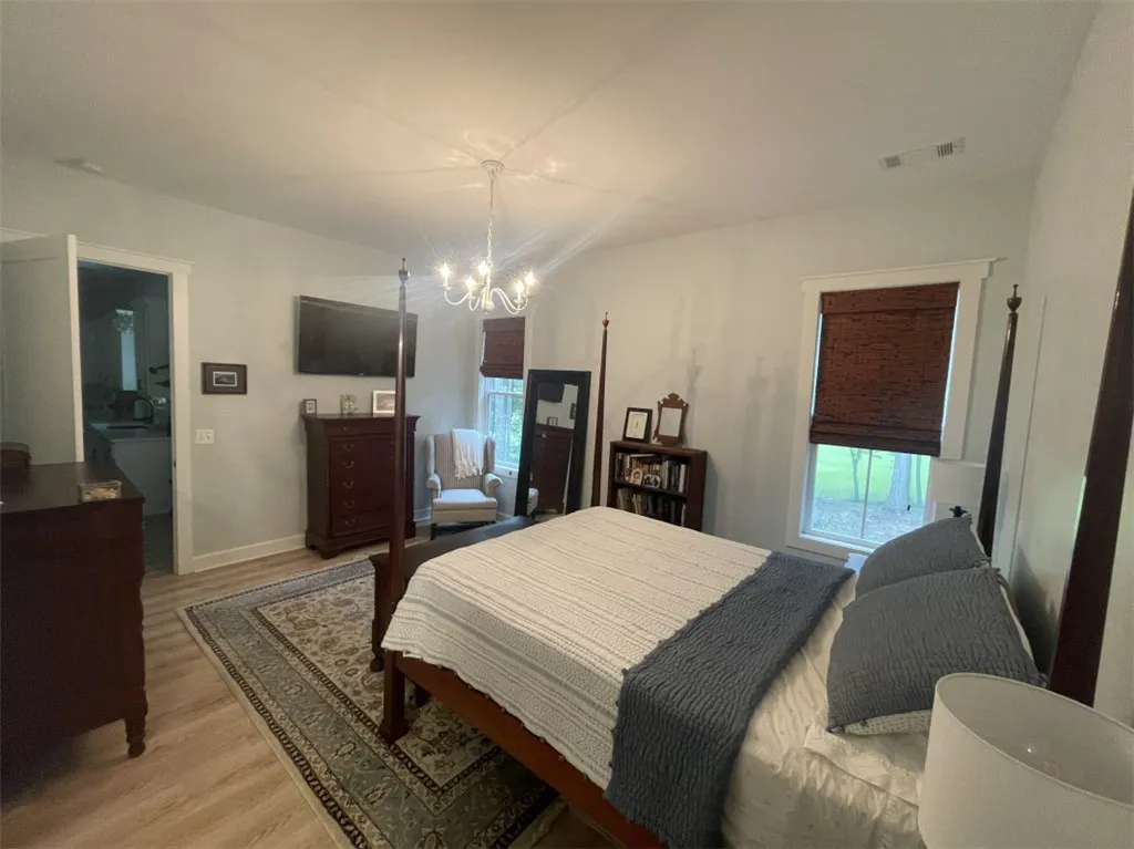 Elegant chandelier lighting graces this spacious primary bedroom, offering a serene retreat.