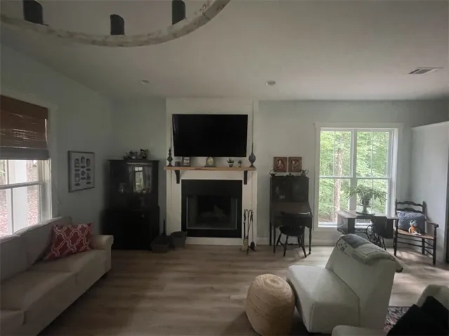 An inviting living room, where light wood flooring complements the bright walls and a prominent fireplace.