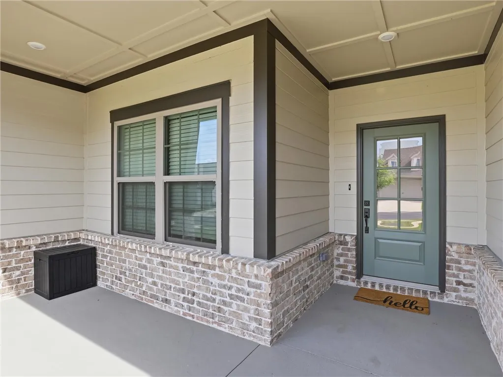 A welcoming covered porch with a sturdy brick foundation and modern siding creates inviting curb appeal.