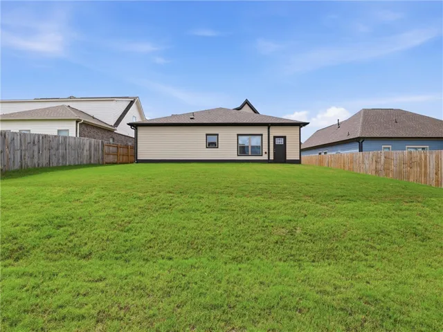 A spacious, verdant yard provides ample outdoor living space behind this well-maintained home.