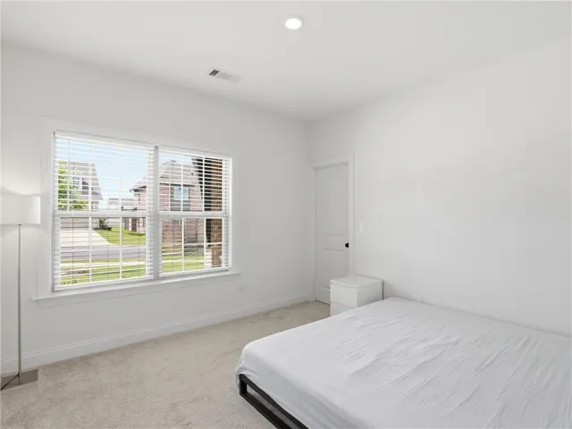 A quiet retreat, this space offers plush carpeted floors and a window with Venetian blinds overlooking the neighborhood.