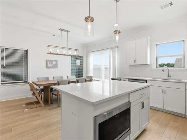 A well-lit culinary space seamlessly flows into the adjacent dining area, creating an ideal setting for gatherings.