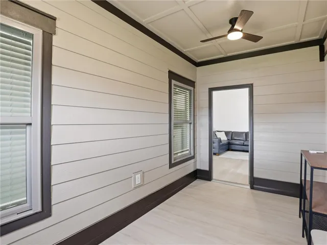 A well-lit screened porch features shiplap walls and a tasteful ceiling fan, offering a serene extension of living space.