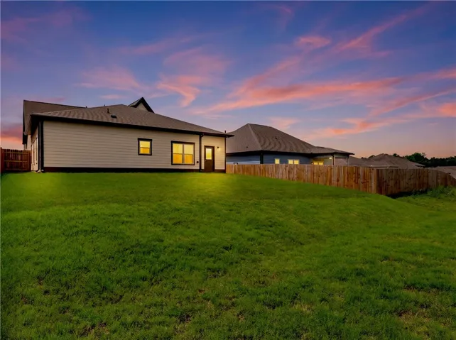 A twilight panorama reveals a generous green yard, ideal for recreation and relaxation.