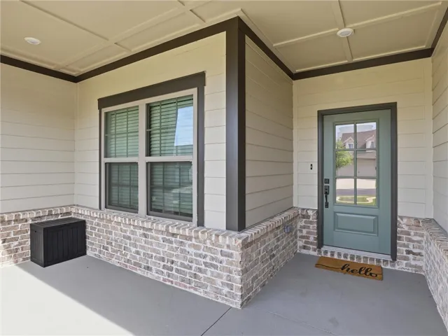 A welcoming covered porch with a sturdy brick foundation and modern siding creates inviting curb appeal.