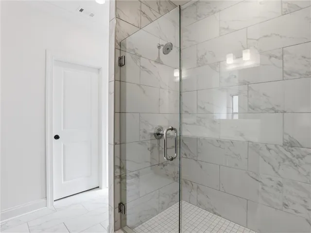 A pristine shower with marbled tile walls and a clear glass enclosure creates a refreshing oasis.