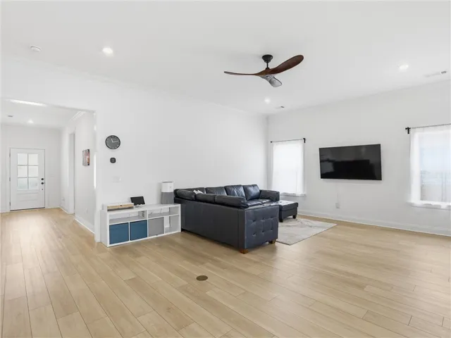 Blonde hardwood floors extend across this bright living area, offering a clean, contemporary aesthetic perfect for relaxed gatherings.