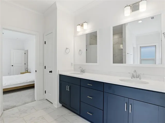 Double vanities with sleek blue cabinetry and elegant white countertops create a functional and stylish primary​​‌​​​​‌​​‌‌​‌‌​​​‌‌​‌​‌​‌​​​‌​​ bathroom.