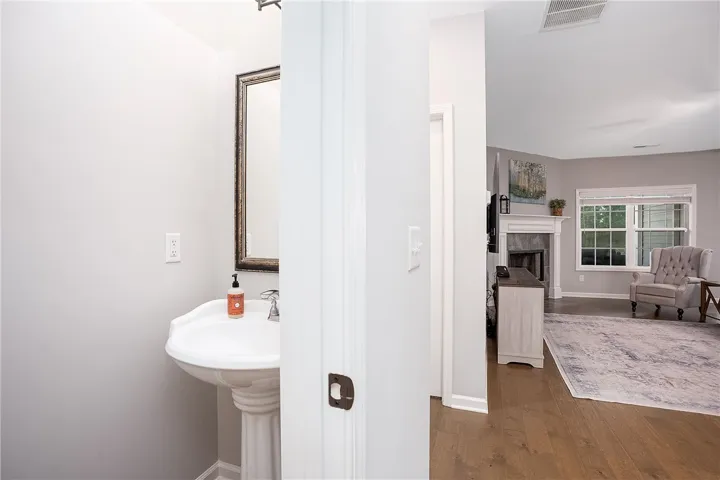Pedestal sink offers a clean design, complementing the rich wood flooring of the adjacent living area.