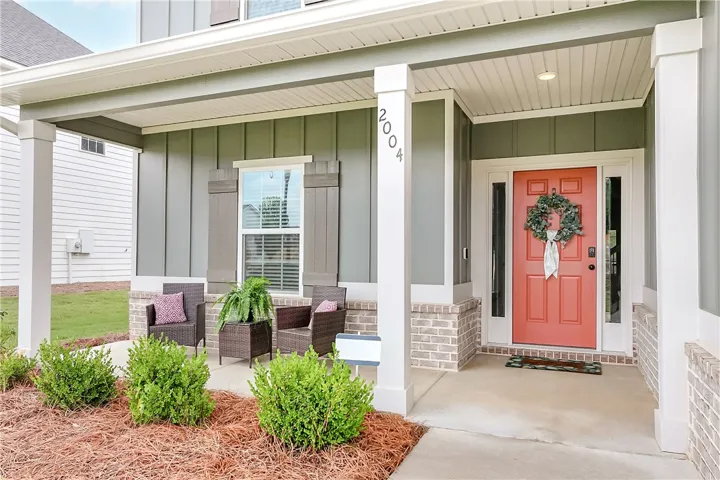 A welcoming covered porch with ample space for outdoor seating and charming brick detailing.