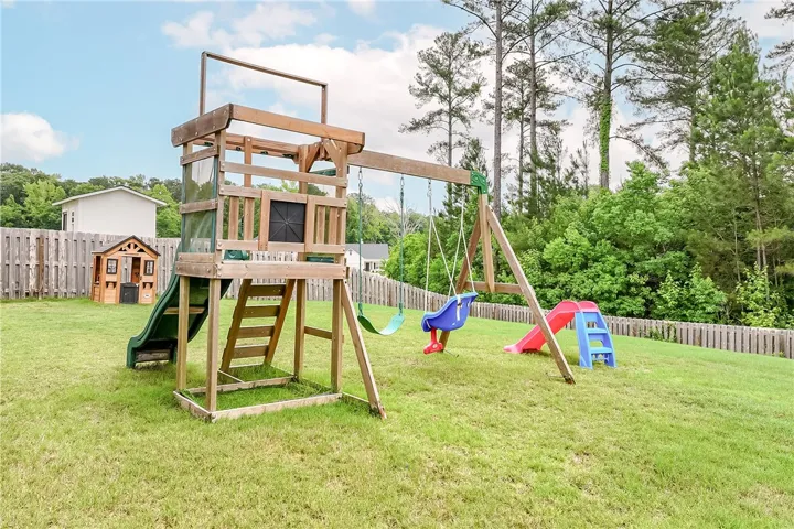 A spacious backyard features a vibrant playset, offering endless outdoor enjoyment.