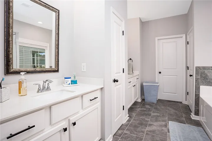 A well-appointed bathroom features a single vanity with stone counters and a spacious soaking tub.