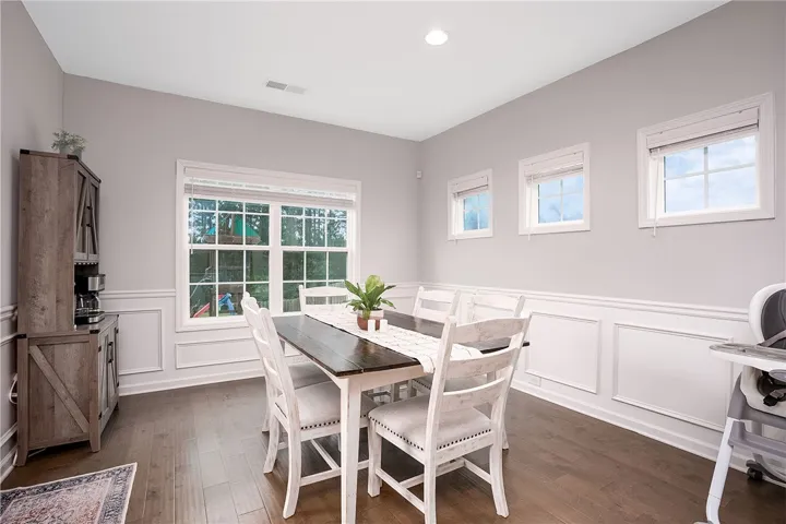 Hardwood floors and wainscoting adorn this well-lit dining space, ready for family meals.