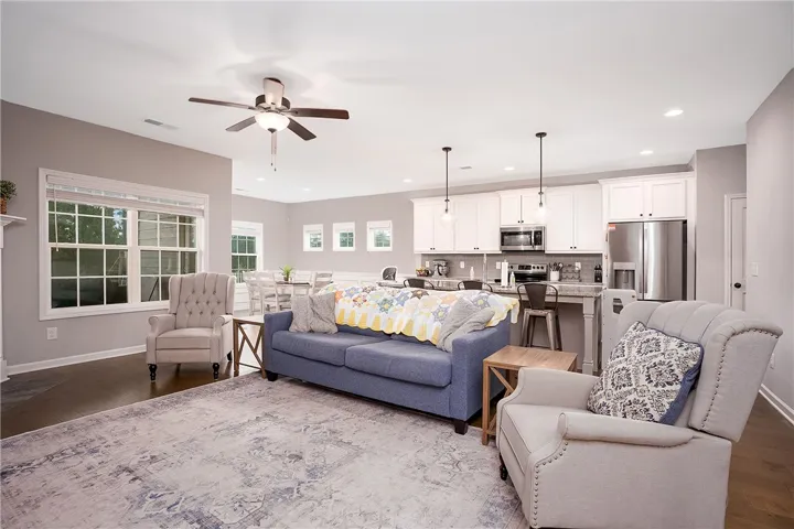 An open concept living area boasts rich hardwood flooring and abundant natural light.
