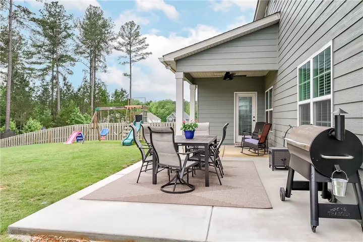 A fenced backyard offers a concrete patio and a playset, perfect for outdoor recreation.