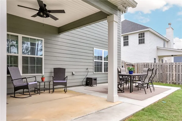 A welcoming patio extends outdoor living space, featuring a cooling ceiling fan and ample room for relaxation and dining.
