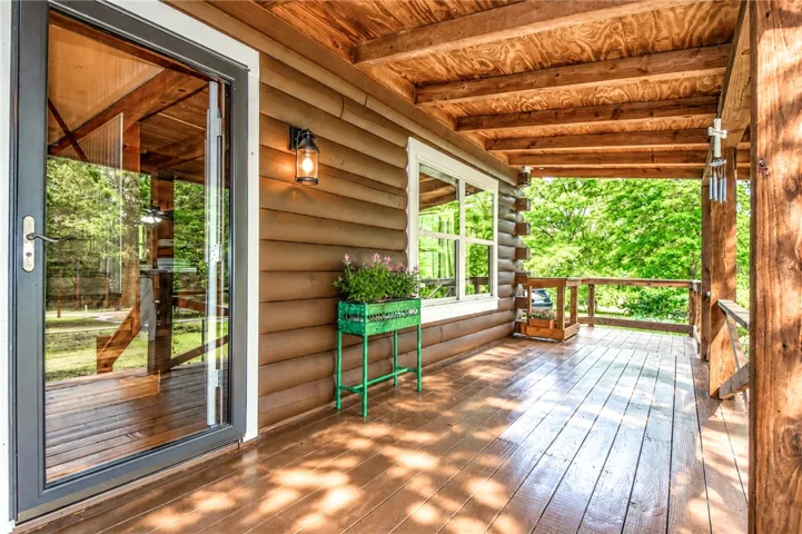 A spacious wood-planked porch extends an inviting outdoor living area, perfect for enjoying the natural surroundings.