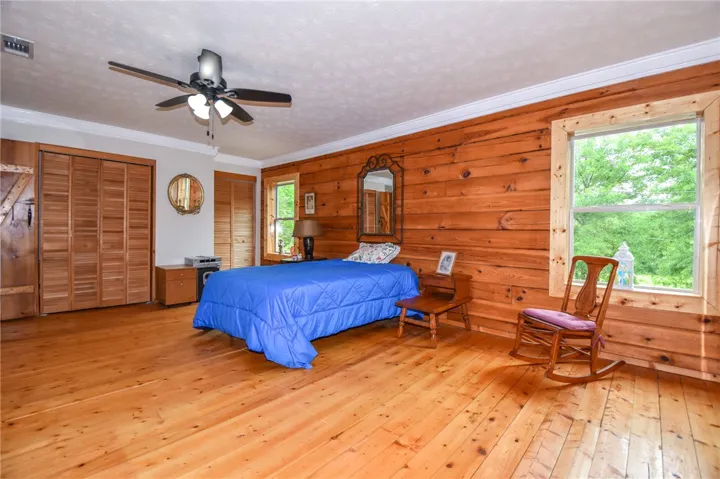 Natural wood paneling and wide-plank flooring create a cozy, cabin-like sleeping area.