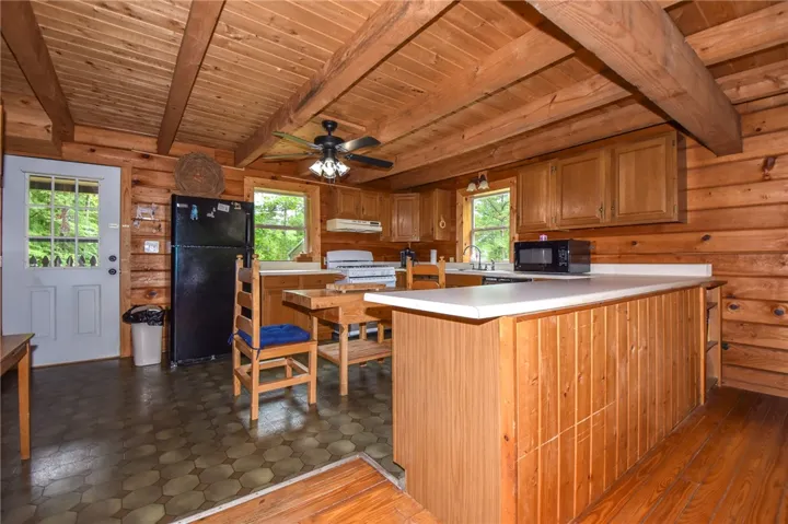 A rustic cabin kitchen boasts exposed wood beam ceilings and wood plank walls, offering a charming, cozy atmosphere.