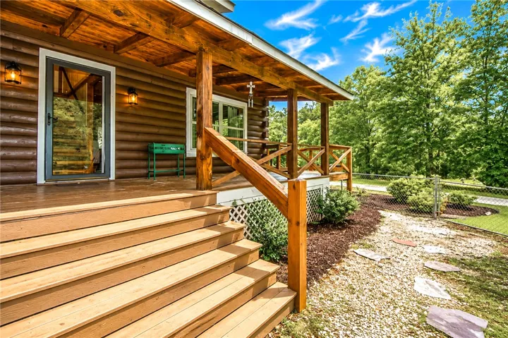 A charming log cabin welcomes with a generous porch and verdant surroundings.