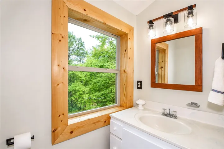 A refreshing bathroom with a broad window framing verdant outdoor scenery.