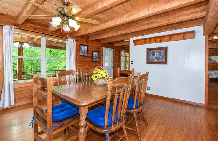 A rustic dining area features wood paneling and exposed beam ceilings, with natural light pouring in from the windows.