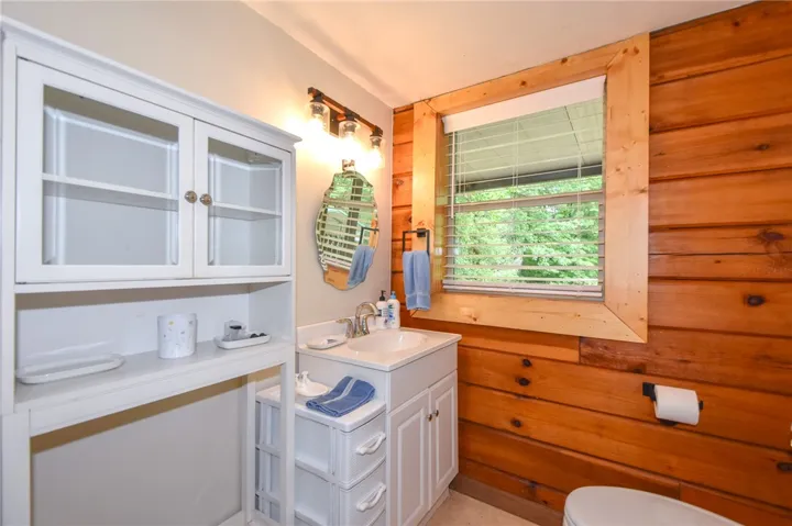 Natural wood paneling and a modern vanity create a balanced aesthetic in this well-appointed lavatory.