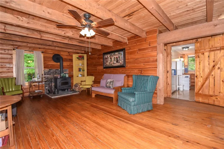 A rustic living area with rich wood walls and exposed beams, anchored by a classic wood-burning stove.