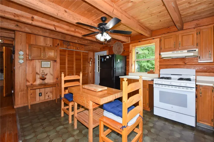A rustic kitchen, well-lit by a large window, offers a functional layout.