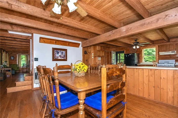 A rustic dining area with exposed wood beams and abundant natural light.