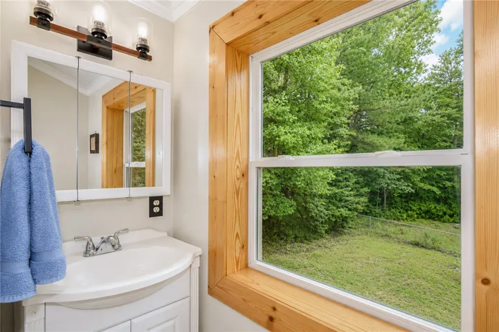 A window in the bathroom offers tranquil, green views of the surrounding natural landscape.