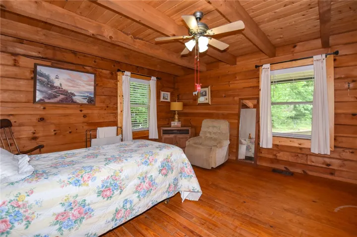 Warm wood walls and ceiling beams provide rustic charm to this peaceful sleeping area.