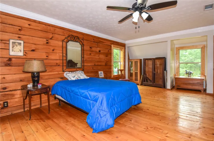 Warm wood paneling and wide-plank floors create a cozy atmosphere in this spacious room.