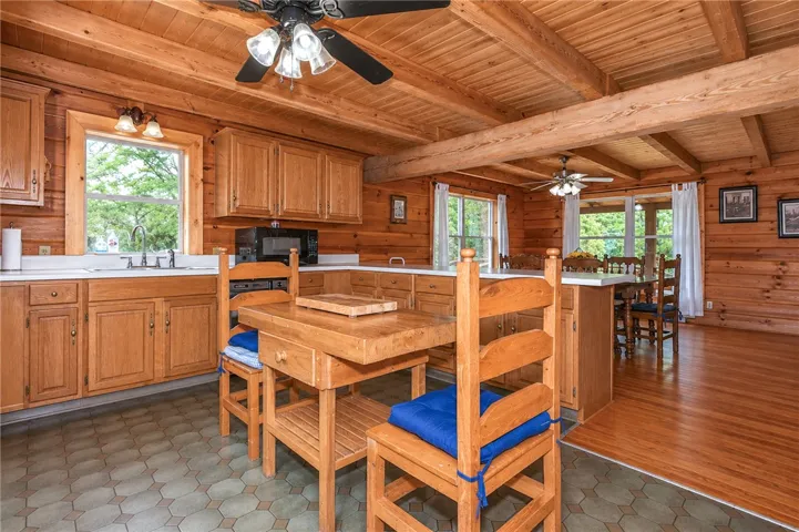 A rustic eat-in kitchen with wood-paneled walls and ceiling, featuring a kitchen island.