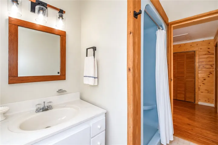 A well-appointed bathroom features a single vanity, wood-framed mirror, and an adjacent shower stall.