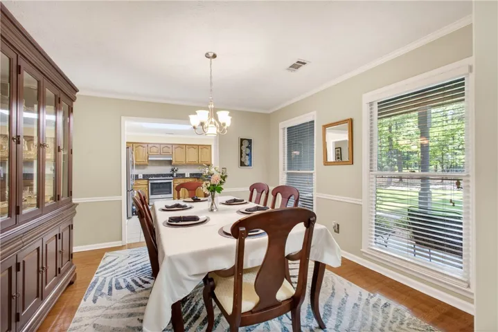 Hardwood flooring and crown molding appoint this elegant dining space with an open kitchen view.