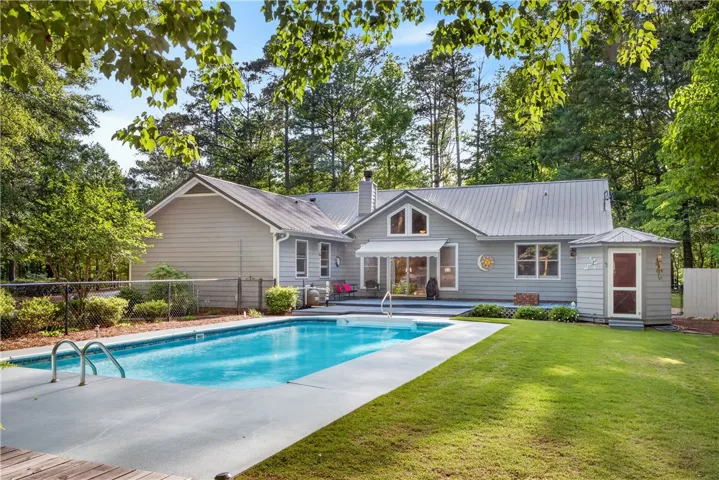 A tranquil backyard oasis featuring a sparkling pool, generous patio space, and a well-tended lawn.