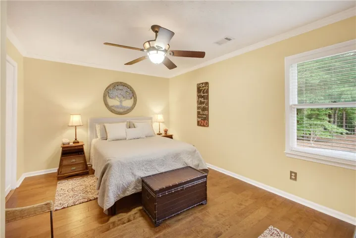 Hardwood floors and a bright window elevate this comfortable sleeping area.