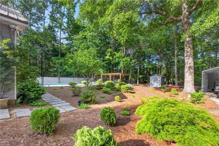A spacious backyard retreat features an inviting in-ground pool, covered patio, and lush landscaping.