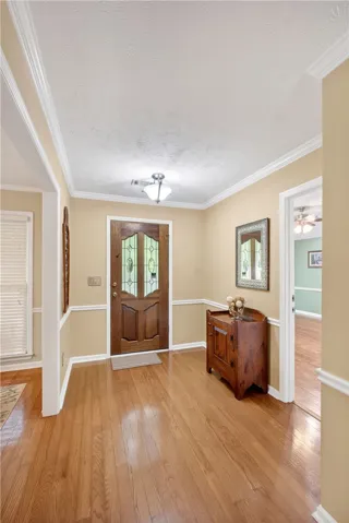 A warm, inviting entryway welcomes all with polished hardwood floors and crown molding.