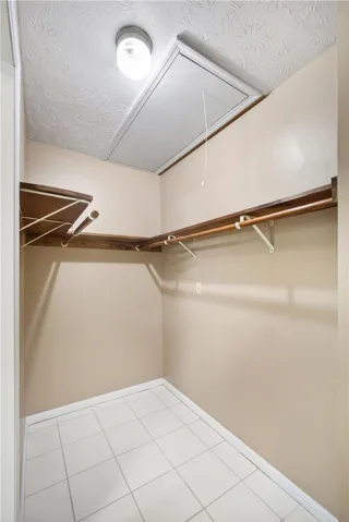 Functional walk-in closet with ample storage solutions and convenient attic access.