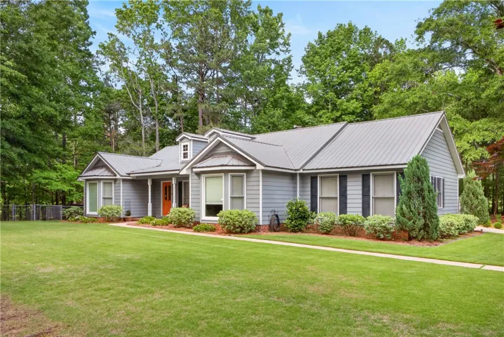 Lush landscaping and a manicured lawn enhance this welcoming home with a vibrant front door.