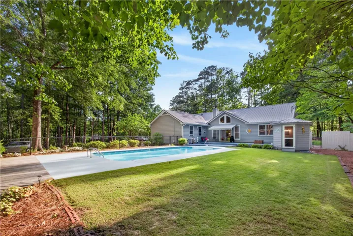 A private backyard oasis features an inviting pool, expansive lawn, and mature trees, perfect for entertaining.