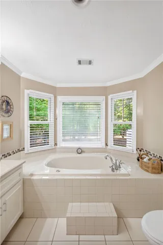 A deep soaking tub sits beneath multiple windows, offering a serene, private retreat.