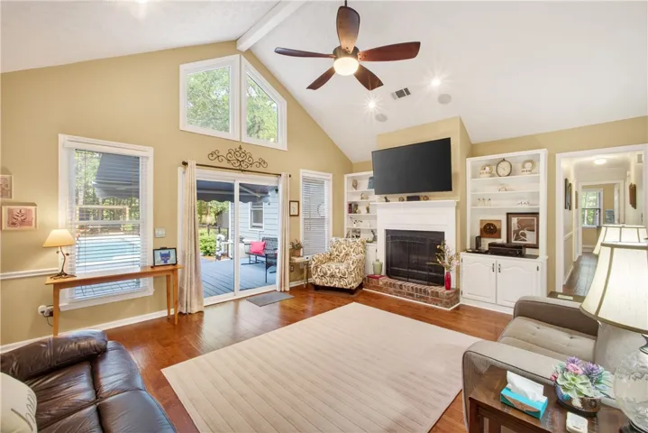 Vast vaulted ceilings and a cozy fireplace anchor this inviting living space, opening onto a private deck.
