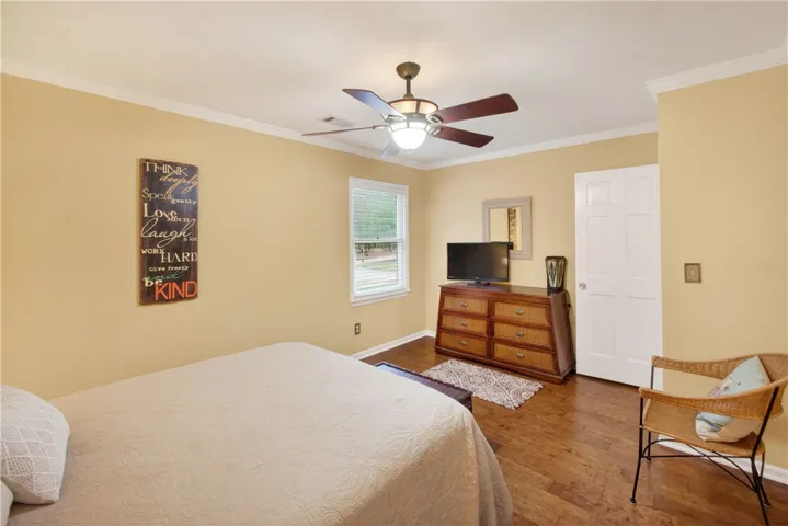 Hardwood floors and a ceiling fan create a comfortable atmosphere in this well-appointed sleeping area.